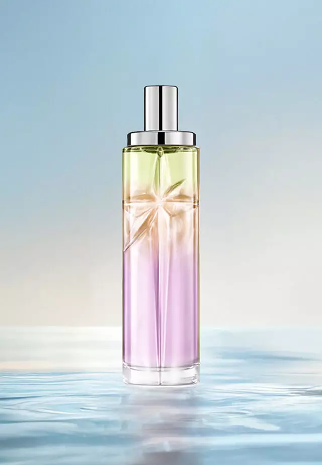 Ricetta di layering Sweet Kiss Starlicious: flacone alto con sfumatura lavanda, ambra e verde chiaro sull'acqua su sfondo blu tenue. Profumo luminoso e fruttato con un tocco gourmand; 3 spruzzi Berry Licorice, 2 Pineapple Musk, 1 Pistachio Praline.