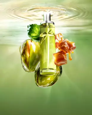 Immagine in stile natura morta del nuovo Starlicious Pistachio Praline, con il flacone sottile circondato dai suoi ingredienti chiave: una foglia di patchouli, pistacchi interi e cubi di caramello gocciolanti, il tutto su uno sfondo di acqua increspata verde luminoso.
