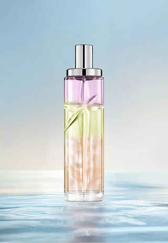 Ricetta di layering Yummy Swirl Starlicious: flacone alto con sfumatura viola, verde e arancione sull'acqua su uno sfondo blu tenue. Profumo cremoso, tropicale, delicatamente nocciolato con un tocco di frutti di bosco; 2 spruzzi Pineapple Musk, 1 Pistachio Praline, 1 Berry Licorice.