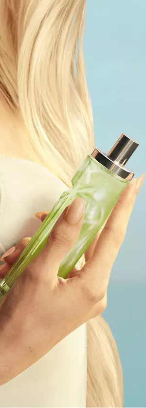 Nuova immagine di un prodotto tenuto in mano di Starlicious Pistachio Praline che mostra una modella con lunghi capelli biondi e occhi azzurri, che indossa un abito giallo pallido e tiene in mano il flacone della fragranza Pistachio Praline.